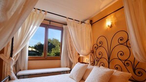 Une chambre à coucher avec un lit, un banc et une fenêtre avec des rideaux.