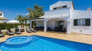 A modern villa with a swimming pool, outdoor seating, and a covered patio.
