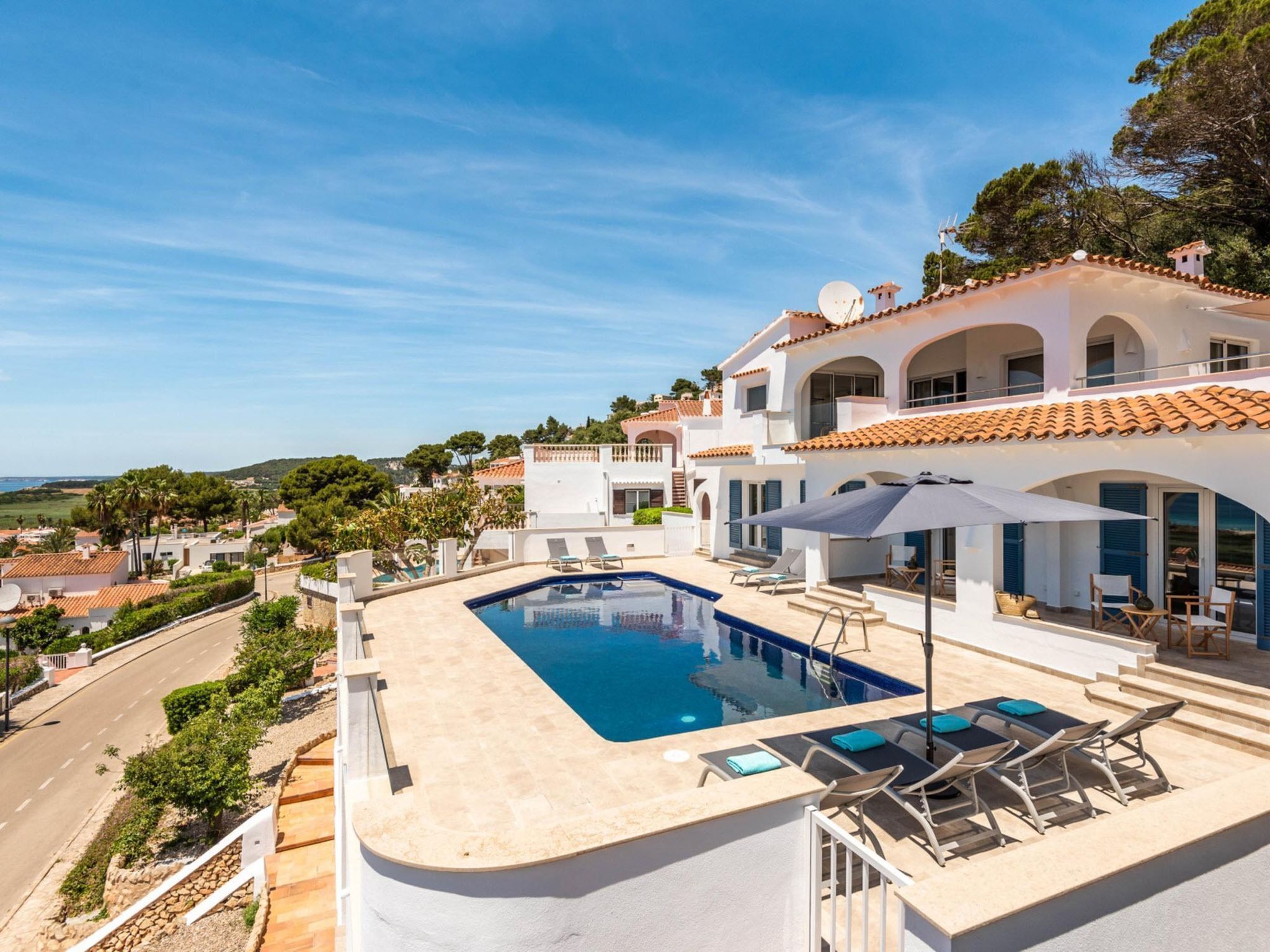 A modern villa with a swimming pool, outdoor seating, and a view of the surrounding landscape.