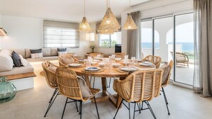 A spacious dining area with a round wooden table set for six, surrounded by wicker chairs. - Villa Atalis by Interhome (Son Bou)