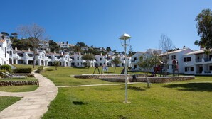 A residential area with white houses, a paved walkway, and a playground.