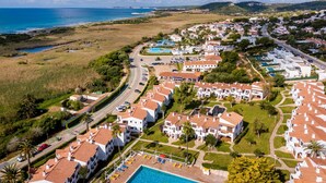 An aerial view of a coastal resort with villas, a swimming pool, and a beach.