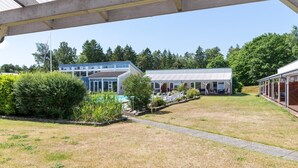 A covered outdoor area with a pool, a building with a blue roof, and a covered seating area.