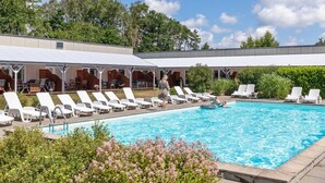 A swimming pool with lounge chairs and a covered seating area.