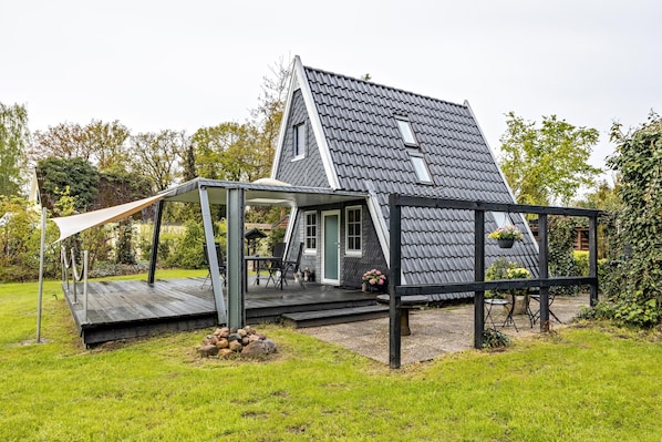 A house with a sloped roof, a porch with outdoor seating, and a garden area.