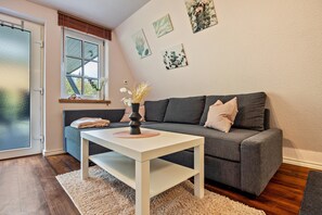A living room with a gray sofa, a white coffee table, a fluffy rug, and a window with blinds.