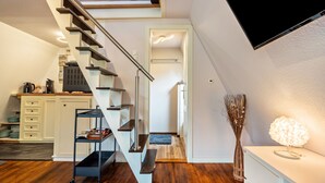 A modern interior with a staircase, a flat-screen TV, and a desk with a lamp. - Holiday Home 'Elbliebe' with Private Terrace, Wi-Fi and Air Conditioning (Dannenberg)
