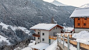 A mountain cabin with a wooden exterior, a balcony, and a snow-covered roof. - Holiday flat "Emma" with mountain view, balcony and WLAN (See)