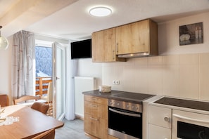 Et moderne køkken med træskabe, en komfur og et spiseområde med et bord og stole.