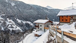 A mountain cabin with a wooden exterior, a balcony, and a snow-covered landscape. - Holiday Apartment "Elena" with Mountain View, Shared Terrace & Wi-Fi (See)