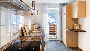 A modern kitchen with a stove, sink, and wooden cabinets. - Holiday Apartment "Elena" with Mountain View, Shared Terrace & Wi-Fi (See)