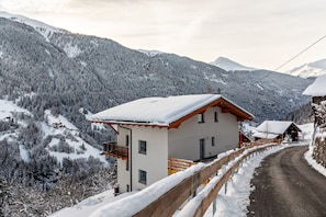 Un village de montagne enneigé, avec un bâtiment d’un seul étage doté d’un balcon et d’une clôture en bois.