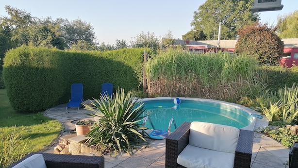 Una piscina amb gandules i un banyera d'hidromassatge en un jardí ben cuidat.