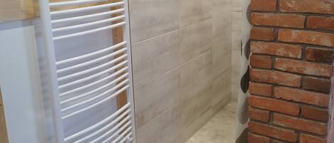 Una habitación con piso de madera, pared de ladrillo y radiador blanco.