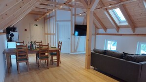 An attic room with a dining table, chairs, a sofa, and a TV. - Apartment 'Kleine Auszeit 1' with Private Terrace and Wi-Fi (Forst)