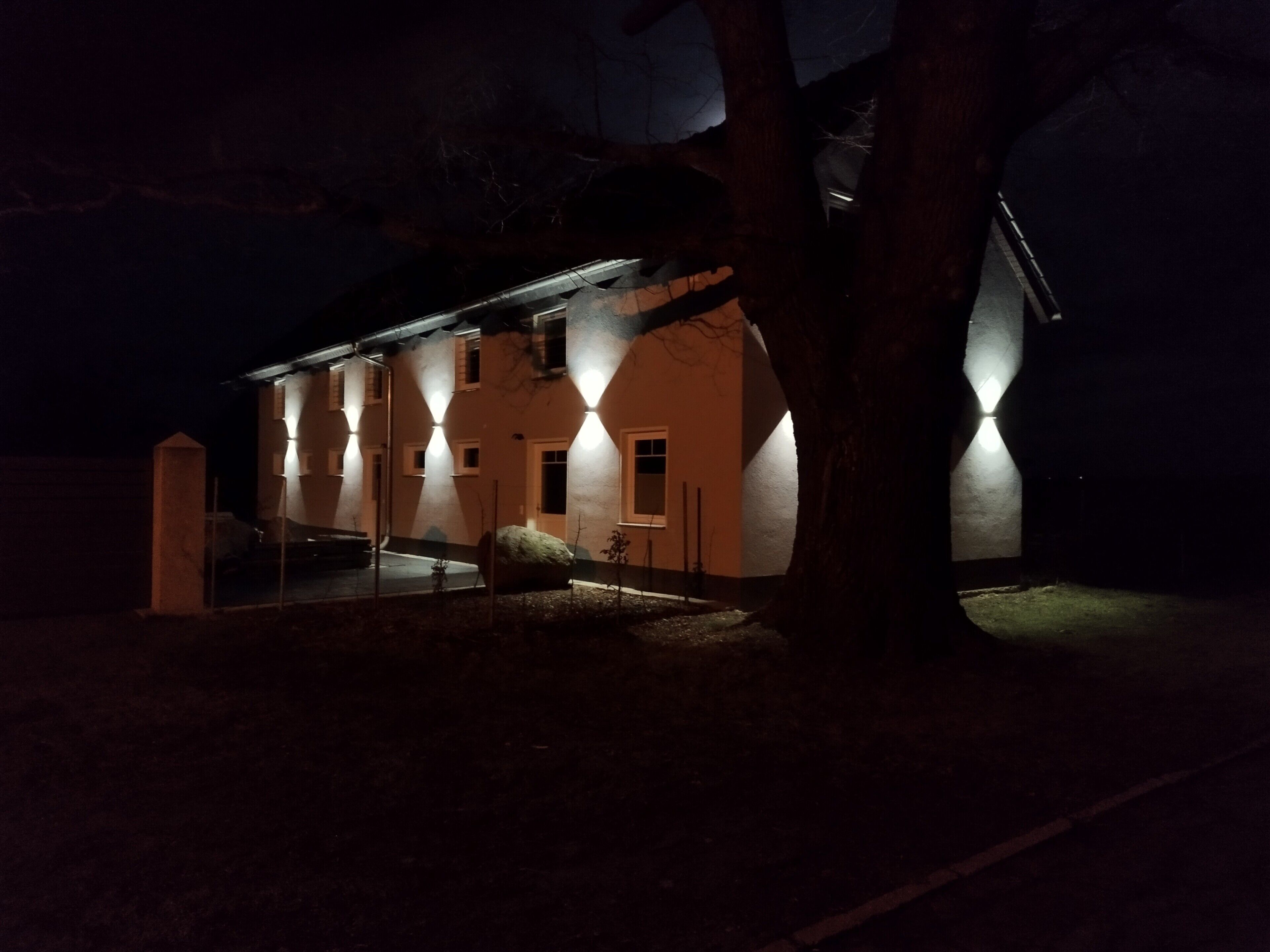 Un bâtiment doté de nombreuses fenêtres et d’une entrée centrale, entouré d’arbres.