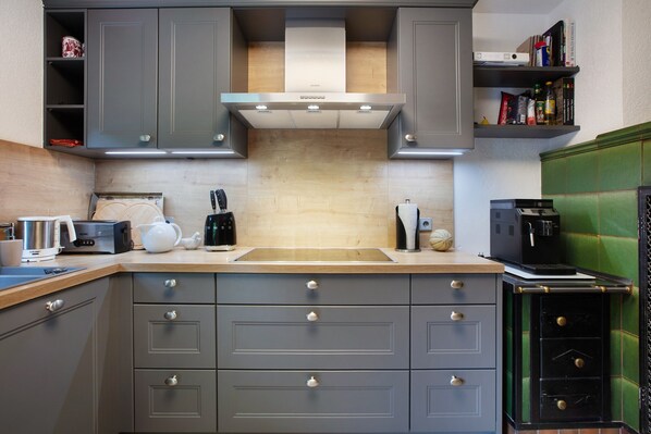 Une cuisine moderne avec des armoires grises, une hotte de cuisinière en acier inoxydable et un plan de travail en bois.