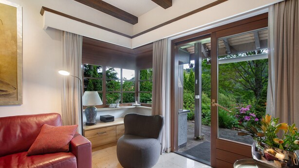A modern living room with a leather sofa, a round chair, a dining table with a vase of flowers, and a view of greenery outside. - Holiday Home 'Amadeus Black Forest Mountain' with Mountain View, Private Terrace and Wi-Fi (Todtmoos)