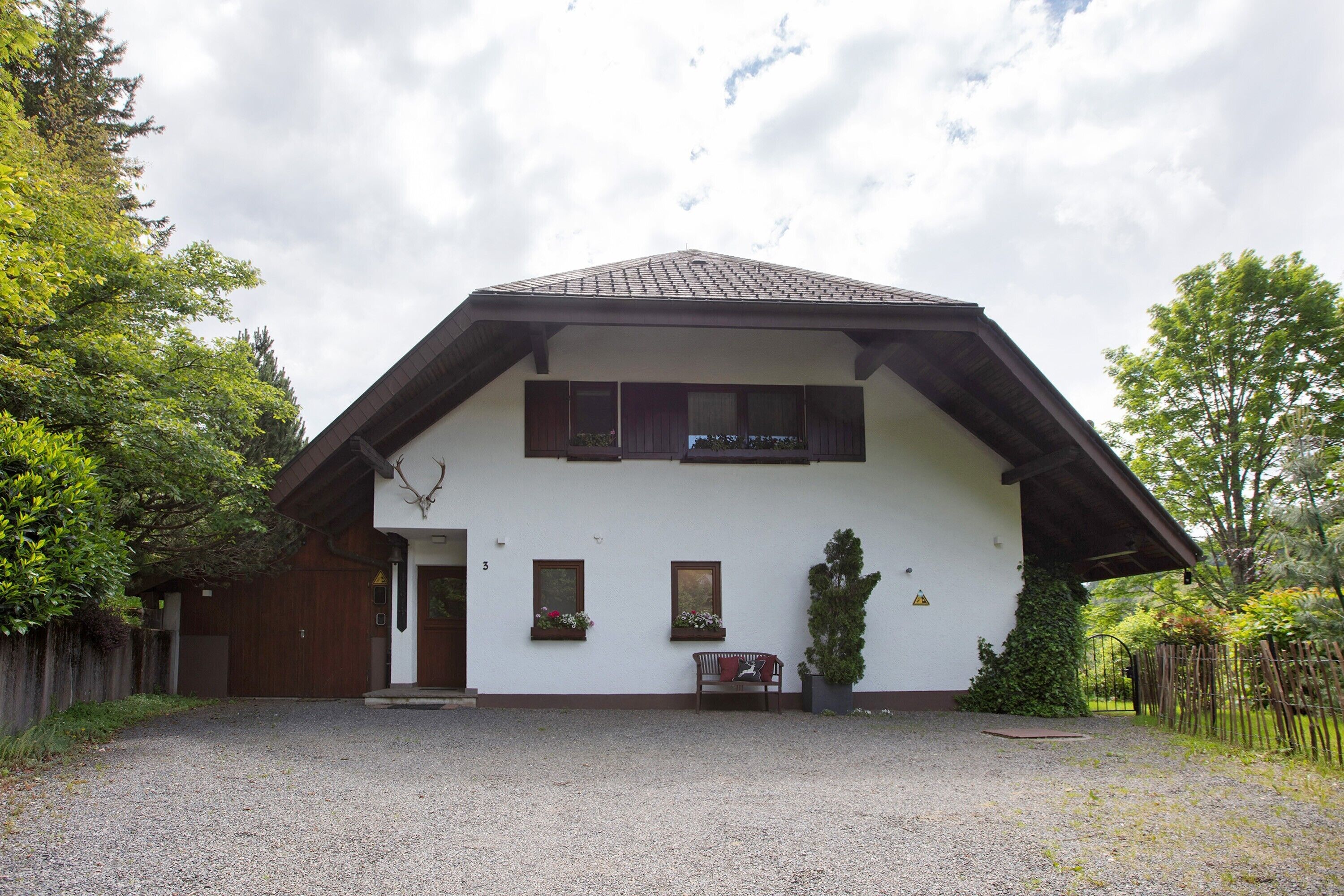 A two-story building with a sloped roof, a wooden door, and a bench outside.