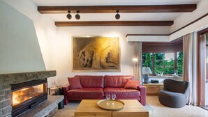 A living room with a fireplace, a red leather sofa, a wooden coffee table, and a large abstract painting on the wall. - Holiday Home 'Amadeus Black Forest Mountain' with Mountain View, Private Terrace and Wi-Fi (Todtmoos)