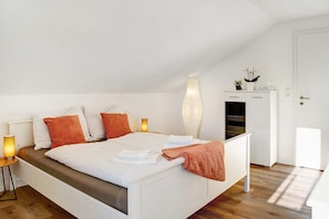 A bedroom with a bed, bedside lamps, a wardrobe, and a small plant on a shelf. - Apartment 'Horst' with Balcony and Wi-Fi (Perach)