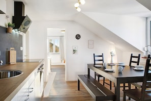 A modern kitchen with a wooden countertop, built-in oven, and a dining area with a bench and chairs. - Apartment 'Horst' with Balcony and Wi-Fi (Perach)