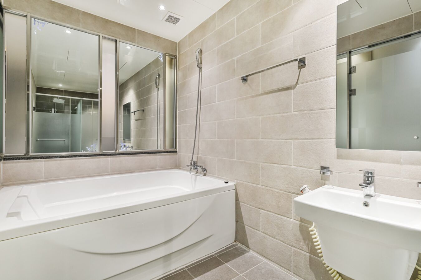 A modern bathroom with a bathtub, a sink, and two mirrors.