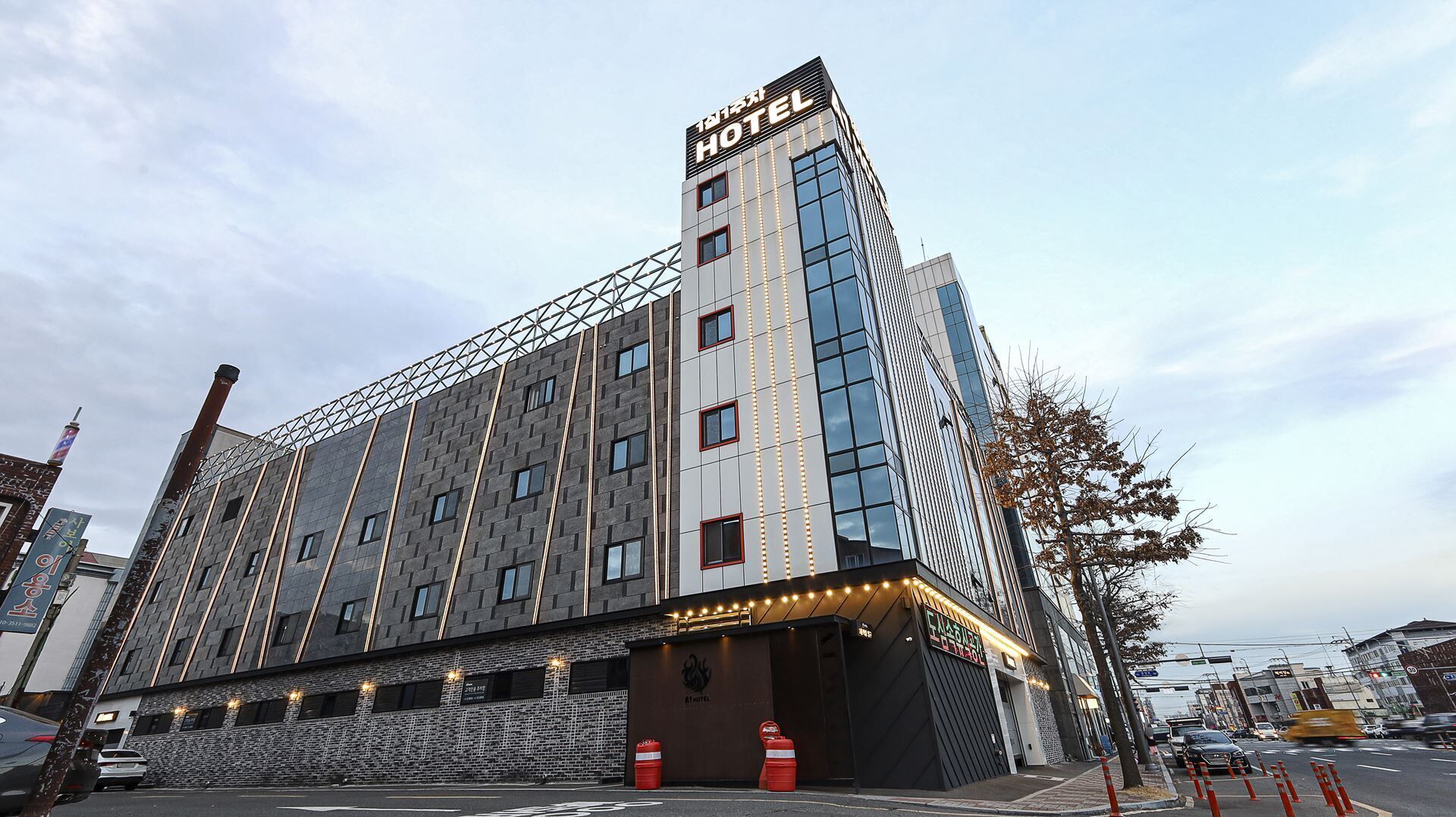 Een modern hotel met een opvallend bord bovenop, een bakstenen gevel en een reeks ramen.