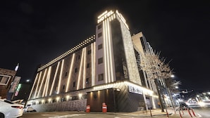 A modern hotel with a prominent corner entrance, multiple floors, and illuminated signage. - Hotel A1 Jukdo (Pohang)