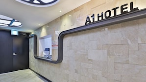 A hotel reception area with a modern design, featuring a marble wall and a large reception desk. - Hotel A1 Jukdo (Pohang)