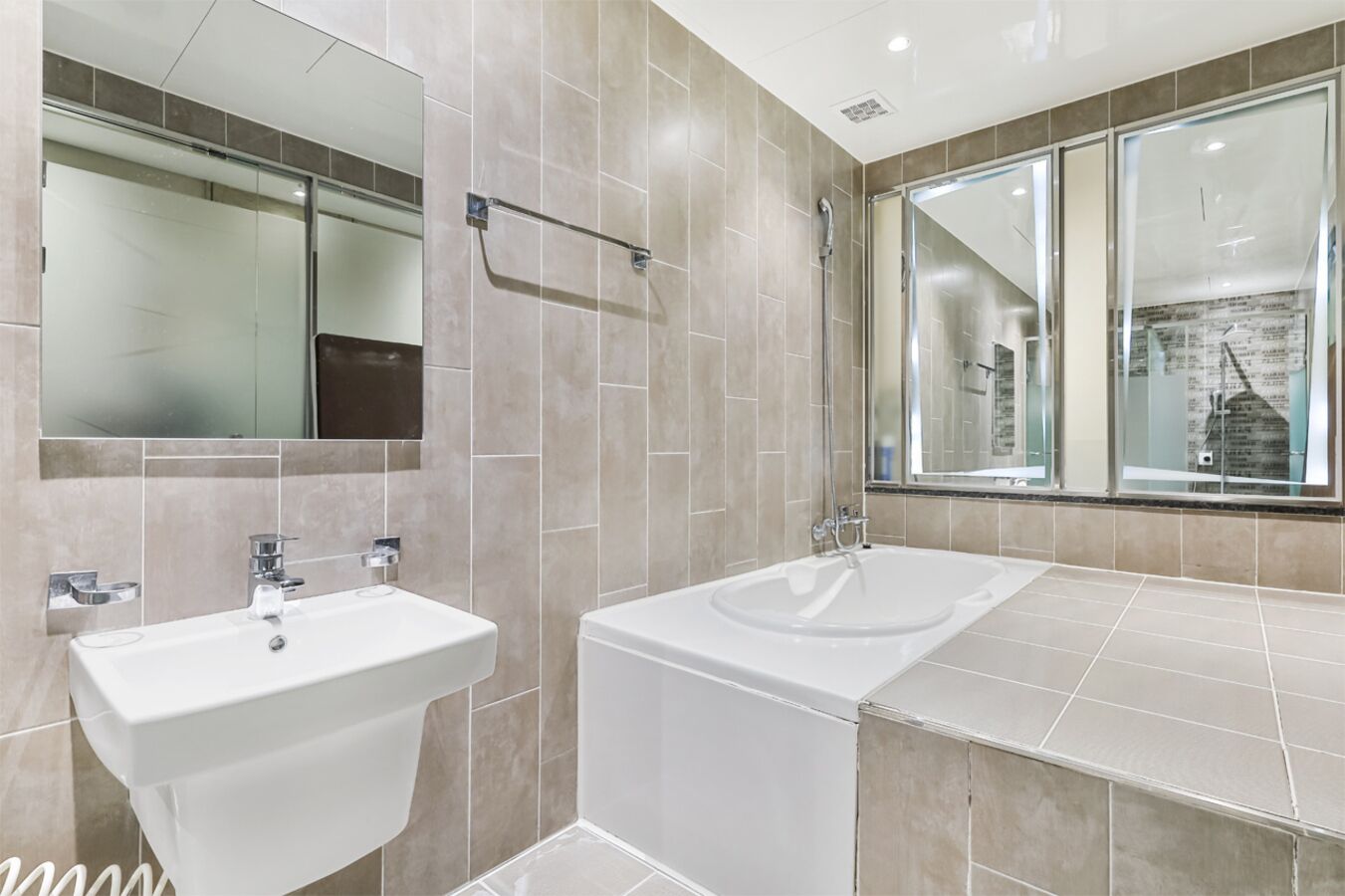 Un baño moderno con dos lavamanos, una bañera y un espejo grande.