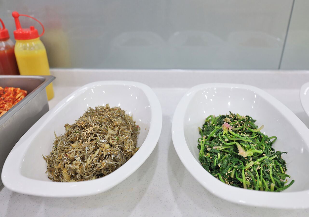 Two white oval dishes containing different food items on a kitchen counter.