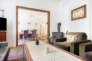 Uma sala de estar com sofá, mesa de centro, lareira e um espaço para refeições ao fundo.