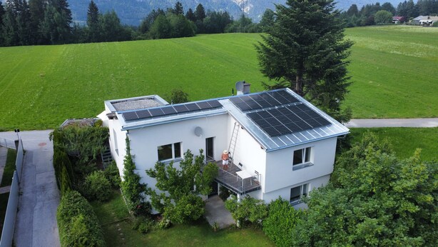 A modern house with solar panels, surrounded by lush greenery and a mountainous backdrop. - Studio Apartment 'Gartenstudio Peony' with Mountain View, Private Terrace and Wi-Fi (Birgitz)