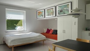 A bedroom with a bed, a sofa, a dining table, and a window with blinds. - Studio Apartment 'Gartenstudio Peony' with Mountain View, Private Terrace and Wi-Fi (Birgitz)
