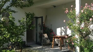 A covered outdoor area with a bicycle, a table, and a chair. - Studio Apartment 'Gartenstudio Peony' with Mountain View, Private Terrace and Wi-Fi (Birgitz)