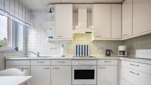 Eine moderne Küche mit weißen Schränken, einem Einbauofen, einer Kaffeemaschine und einem Fenster mit Blick.