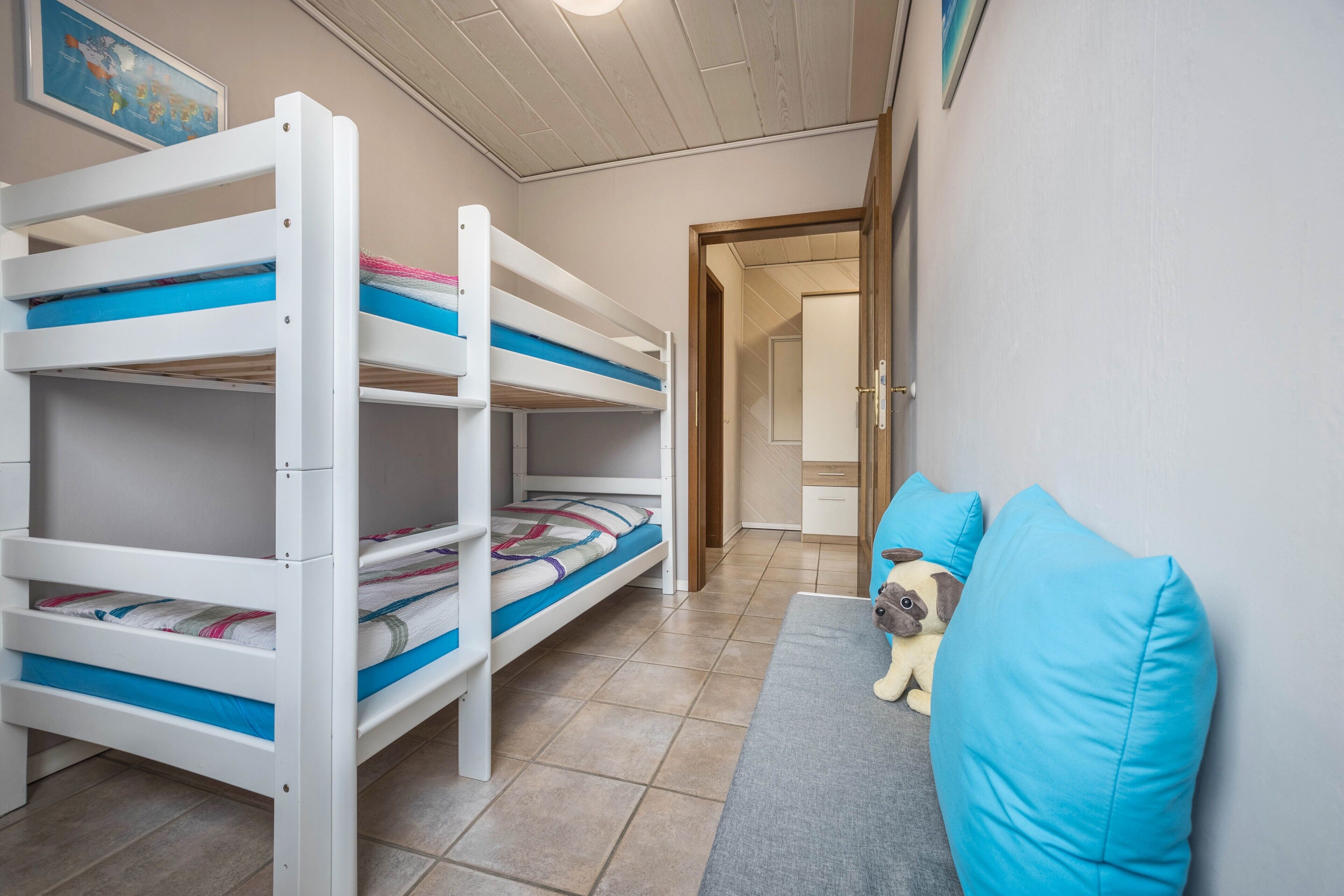Ein Schlafraum mit Etagenbetten, einem grauen Sofa und einem Hundespielzeug.