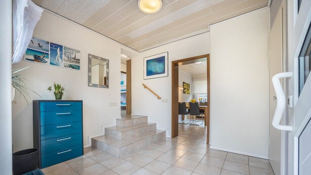 Ein Flur mit einem blauen Schrank, einer Treppe und einem Essbereich im Hintergrund.