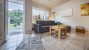 Ein modernes Wohnzimmer mit einer Couch, einem Couchtisch und einer Schiebeglastür, die auf eine Terrasse führt.