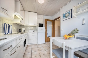 A compact kitchen with white cabinets, a microwave, a coffee maker, and a refrigerator.
