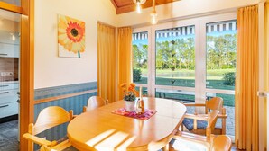 Ein Essbereich mit einem Holztisch, Stühlen, einer Blumenvase und einem Gemälde an der Wand.