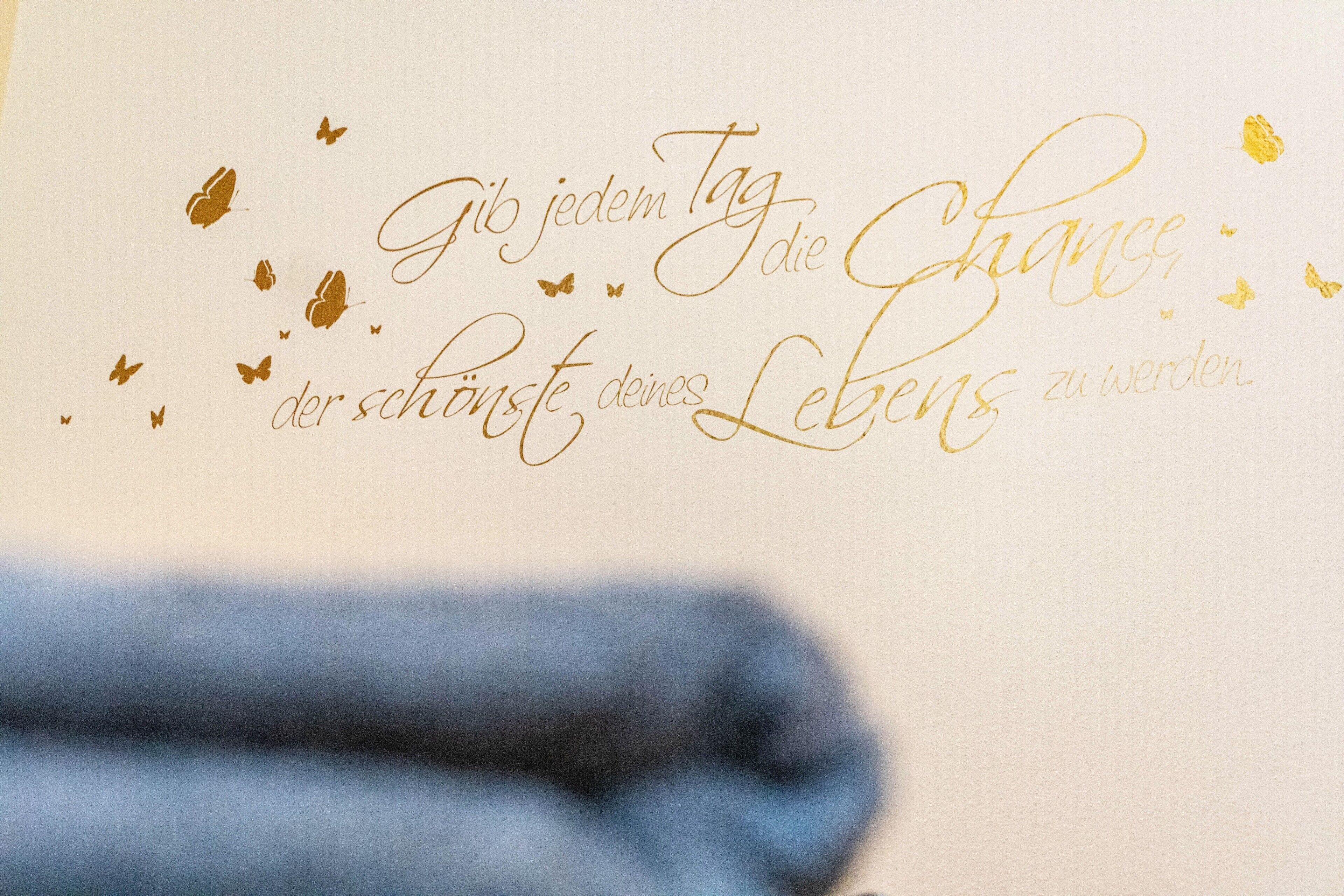 Ein Detailaufnahme eines dekorativen Schildes mit Text und Schmetterlingsmotiven.