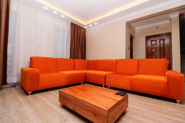 A living room with a sectional sofa, a wooden coffee table, and a door in the background.