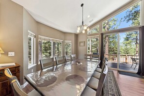 A spacious dining area with a large table, chairs, and a view of the outdoors.