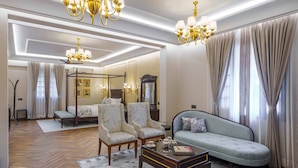 Un salón amplio con un sofá grande, dos sillones, una mesa de centro y una araña.