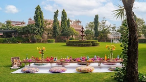 Un jardín con mesa de picnic, sombrillas y una fuente al fondo.