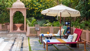 Un patio jardín con un pabellón, sillas de descanso y una mesa con una bebida.