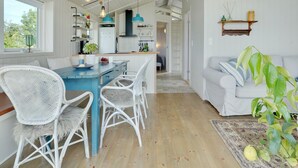 A spacious living area with a dining table, white wicker chairs, a sofa, and a large potted plant. - "Liutulf" - 40m from the sea by Interhome (Haderslev)