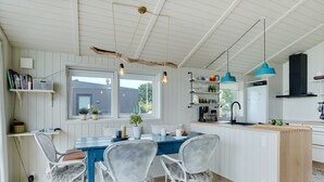 A modern kitchen with a blue dining table, white wicker chairs, and a wooden island. - "Liutulf" - 40m from the sea by Interhome (Haderslev)